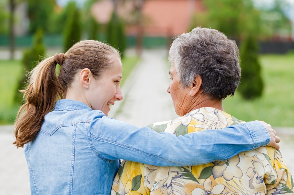 young woman sitting next to elderly woman talking about elder abuse prevention